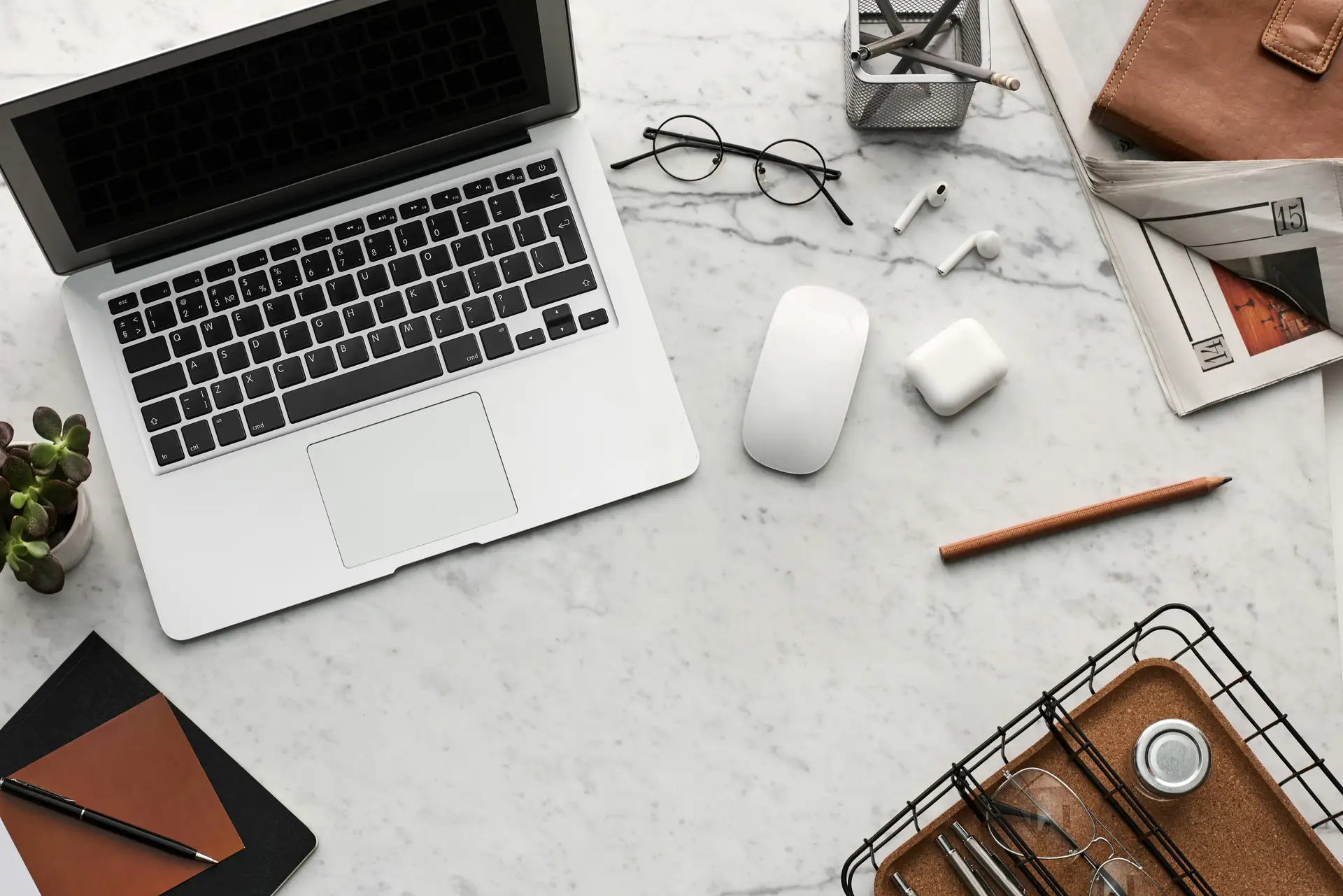 Discover a clean organized workspace featuring a laptop AirPods and stationery essentials on a marble desk